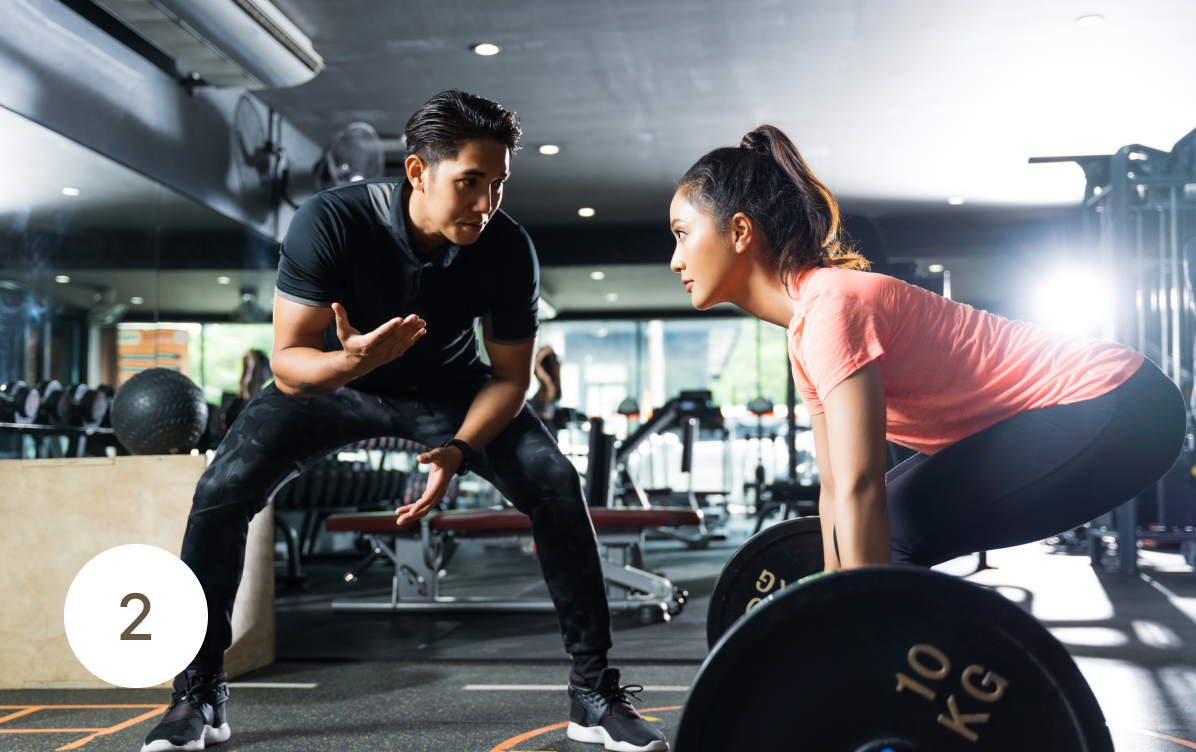 personal trainer assessing client in a gym